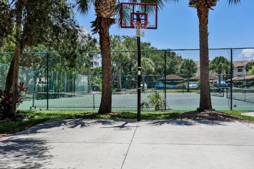 a basketball hoop on a tennis court with palm trees at Midnight Cove II 823 in Siesta Key