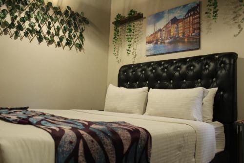 a bedroom with a bed with a black leather headboard at Ghazrins Garuda JB in Johor Bahru