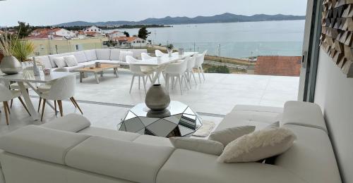 a living room with a white couch and tables and chairs at Villa Zadar Superior in Zadar