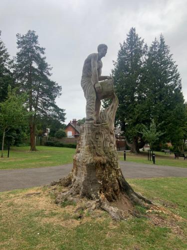 a statue of a man sitting on top of a tree stump at Enjoy your stay at Chorley Road in Droitwich