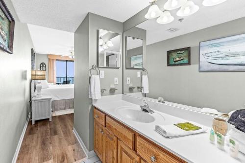 une salle de bain avec un lavabo, un miroir et un lit dans l'établissement Phoenix 5 Unit 506, à Orange Beach
