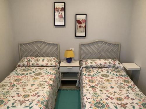 Dos camas en una habitación con un escritorio y dos camas. en Apartamentos Costamar, en Arona