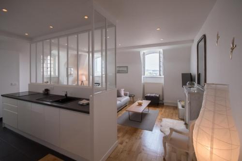 Il comprend une cuisine blanche avec un évier et un salon. dans l'établissement Appartement 4 chambres vue mer Intra-Muros, parking inclus, à Saint-Malo