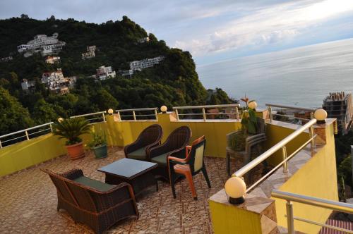 a balcony with chairs and a table and a mountain at Akhmed Guest House in Kvariati