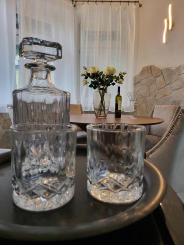a glass bottle and two glasses on a table at Apartment Villa Hřensko 132 in Hřensko