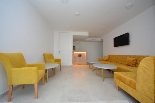 a living room with yellow chairs and a couch and tables at Miss Saray in Sarajevo