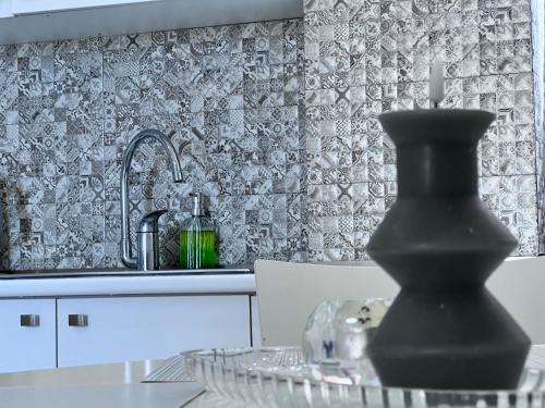 Una cocina con un fregadero y un jarrón negro sobre una mesa. en STUDIO near the Round garden, en Tiflis