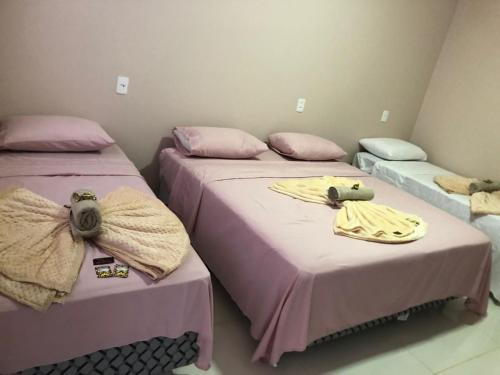 two beds in a room with pink sheets at Pousada Amanhecer no Jalapão in São Félix do Tocantins