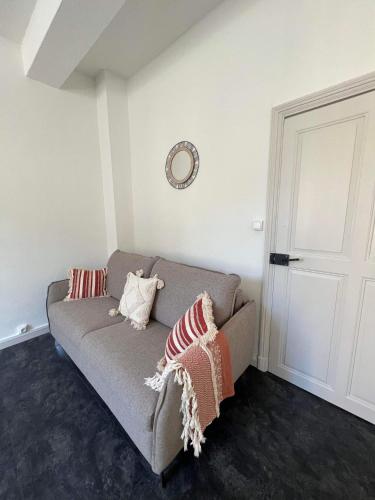 a living room with a couch and a clock on the wall at Appart " la rue des roues", à Fontaine-de-Vaucluse in Fontaine-de-Vaucluse