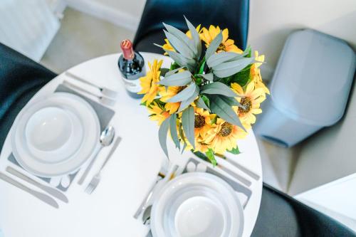 a table with a vase of sunflowers on it at Modern apartment in Crewe by 53 Degrees Property, ideal for long-term Business & Contractors - Sleeps 4 in Crewe