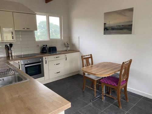 eine Küche mit einem Tisch, Stühlen und einem Waschbecken in der Unterkunft Beautiful Rural Self Contained Farm Annex in Hordle
