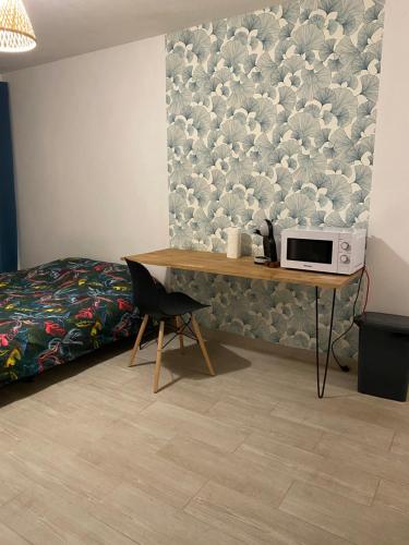 a bedroom with a bed and a table with a microwave at Studio cosy - Sainte-Clotilde in Saint-Denis