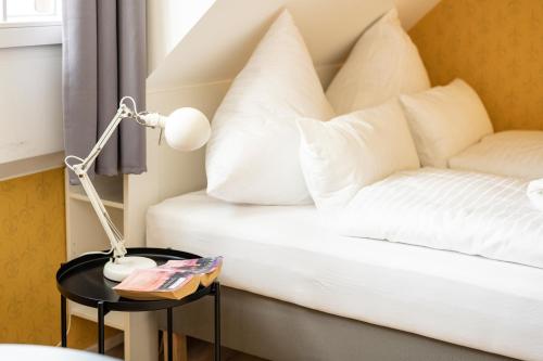 a bed with white pillows and a lamp on a table at Gästehaus am Schlossplatz Z. 3 in Meersburg