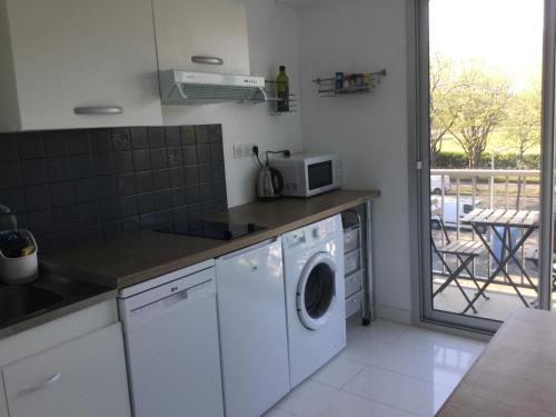 une cuisine avec un lave-linge et un micro-ondes dans l'établissement T1 parc paysager St Nazaire, à Saint-Nazaire