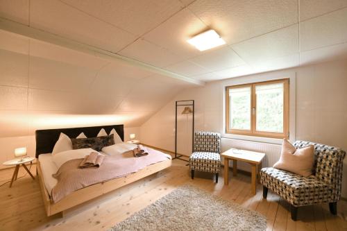 a bedroom with a bed and a chair and a window at Edelweiß am Öberle in Au im Bregenzerwald