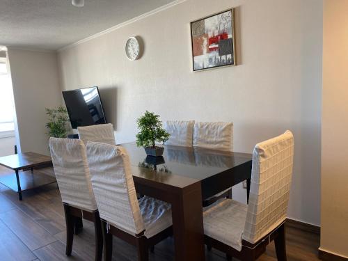 a dining room table with white chairs and a television at Dpto 1er nivel en La Serena in Coquimbo