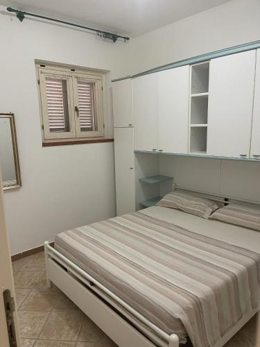 una camera bianca con un letto e una finestra di Appartamento La Guglia a Cala Gonone