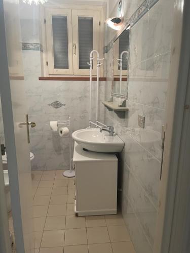 bagno bianco con lavandino e doccia di Appartamento La Guglia a Cala Gonone