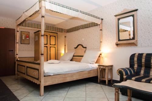 ein Schlafzimmer mit einem Himmelbett und einem Stuhl in der Unterkunft Hotel Borchers in Dörpen