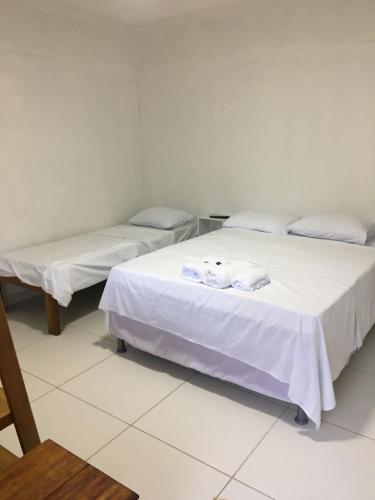 two beds in a room with white sheets and towels at Casa da Gina in Santa Cruz Cabrália