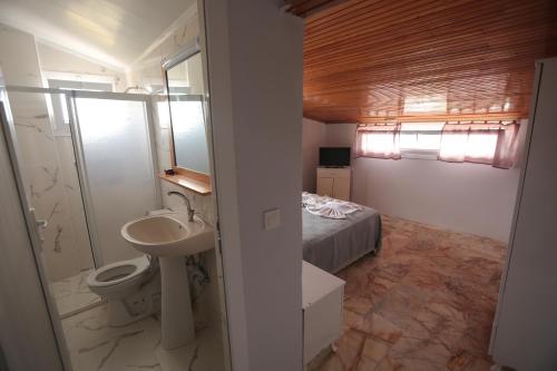 a bathroom with a sink and a toilet and a bed at Ciftlik Hotel in Çeşme