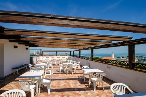a patio with tables and chairs and the ocean at New Bristol Sport Hotel in Cesenatico