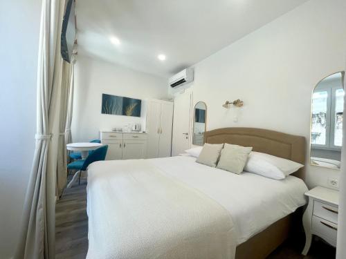a bedroom with a white bed and a blue chair at Ida Old Town Rooms in Dubrovnik
