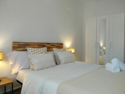 a white bedroom with a large white bed with pillows at Atalaya de los Bermejales in Los Morales