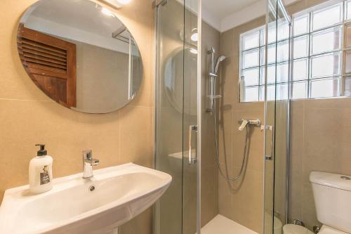 a bathroom with a sink and a shower with a mirror at Chalet Heliconia in Santa Cruz de Tenerife