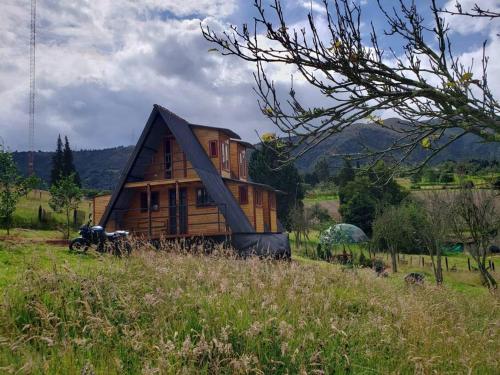 ein kleines Holzhaus auf einem Grasfeld in der Unterkunft Chalet Villa Ines un paraiso en las montañas in Duitama