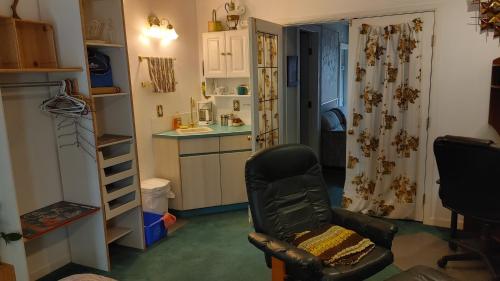 a living room with a chair and a kitchen at Beds By the Bridge in Kelowna