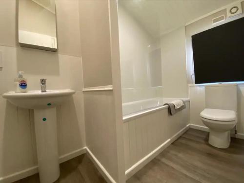 a white bathroom with a sink and a toilet at Lakeside cabin set in the Kentish countryside in Bethersden