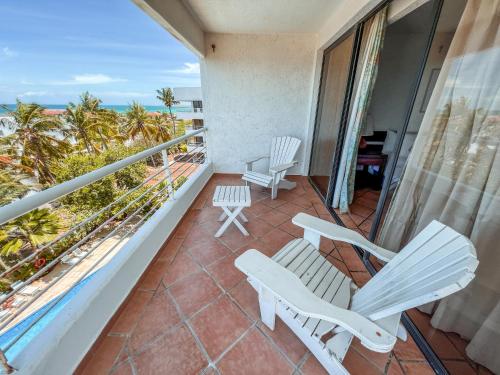 a balcony with white chairs and a view of the ocean at Hotel California Playa El Yaque in El Yaque