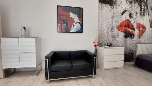 カポリーヴェリにあるChez Nousの黒い椅子と壁に絵画が飾られたベッドルーム1室