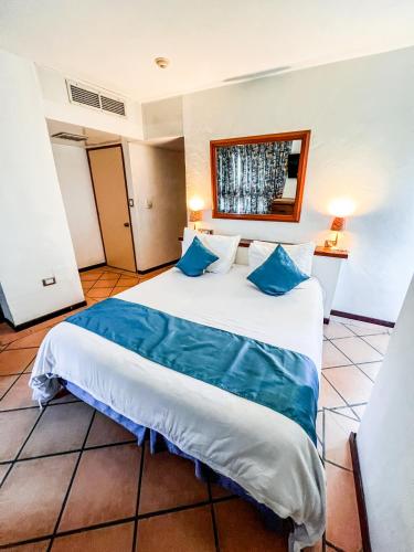 a bedroom with a large white bed with blue pillows at Hotel California Playa El Yaque in El Yaque