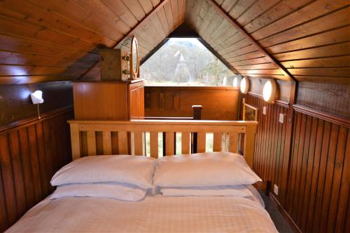 a bed in a wooden room with a window at Iona Lodge in Dalavich