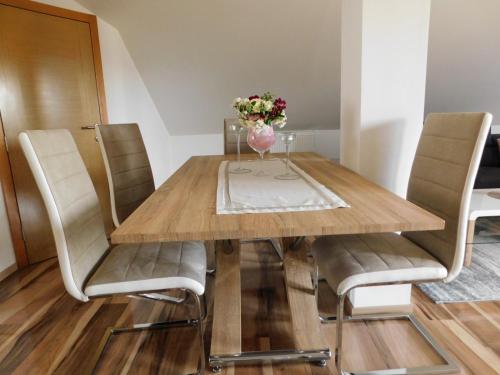 a dining room table with chairs and a vase of flowers at Apartman Lara in Otočac