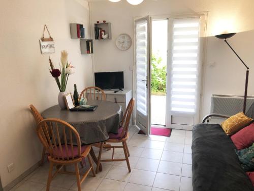 ein Wohnzimmer mit einem Tisch, Stühlen und einem Sofa in der Unterkunft Appartement cosy 100m plage de Pentrez in Saint-Nic