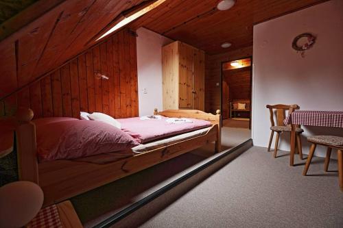 een slaapkamer met een bed met een houten muur bij Penzion a Restaurace U Paseků in Harrachov