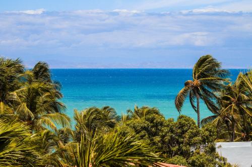 a view of the ocean from a resort with palm trees at Hotel California Playa El Yaque in El Yaque
