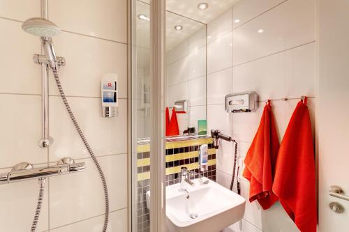 a bathroom with a sink and a shower at MEININGER Hotel Frankfurt Main / Airport in Frankfurt/Main