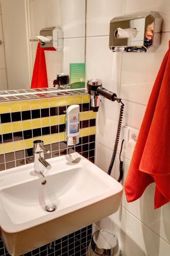 a bathroom with a sink and a red towel at MEININGER Hotel Frankfurt Main / Airport in Frankfurt/Main