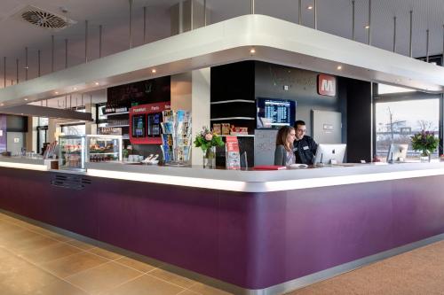 two people standing at a counter in a restaurant at MEININGER Hotel Frankfurt Main / Airport in Frankfurt/Main