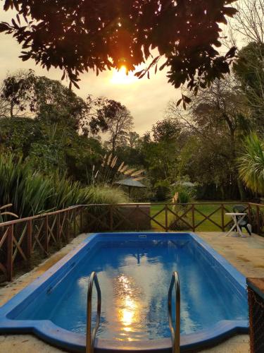 una piscina azul con puesta de sol en el fondo en Studios La Bella Vida en Escobar en Belén de Escobar