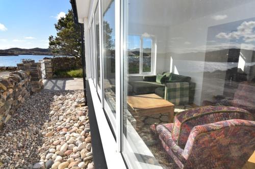 a room with a balcony with a couch and a chair at Culkein Lodge in Drumbeg