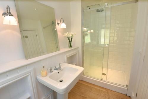 a white bathroom with a sink and a shower at Culkein Lodge in Drumbeg