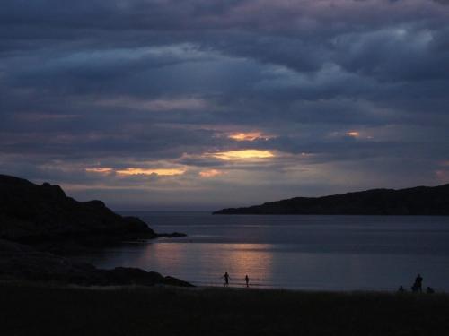 a group of people walking on the beach at sunset at Culkein Lodge in Drumbeg