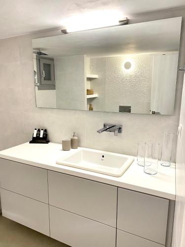a white bathroom with a sink and a mirror at Gerani Deluxe Houses 2 in Astypalaia Town