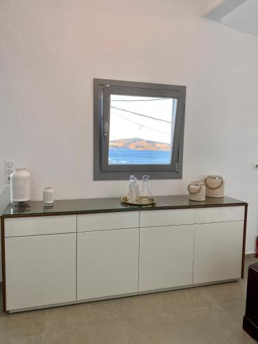 a kitchen with a counter with a window on it at Gerani Deluxe Houses 2 in Astypalaia Town