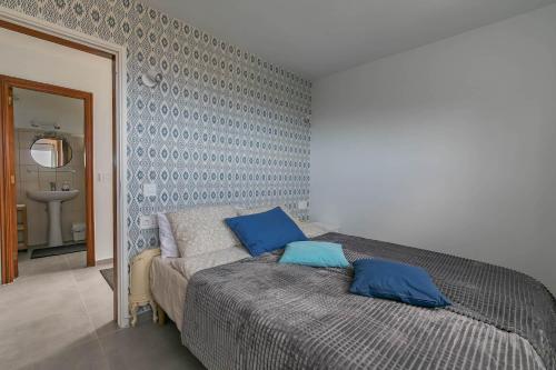 a bedroom with a bed with blue pillows on it at Rosa Challet in Santa Úrsula